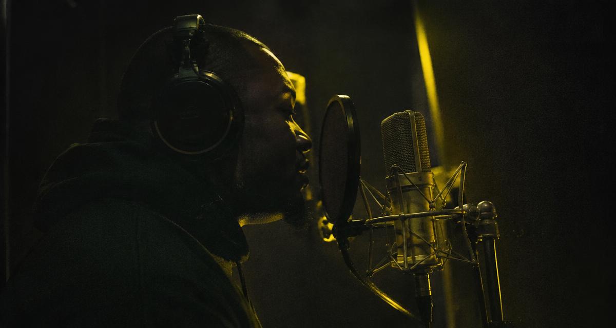 Rapper organizing vocal recordings and buyer notes in a home studio